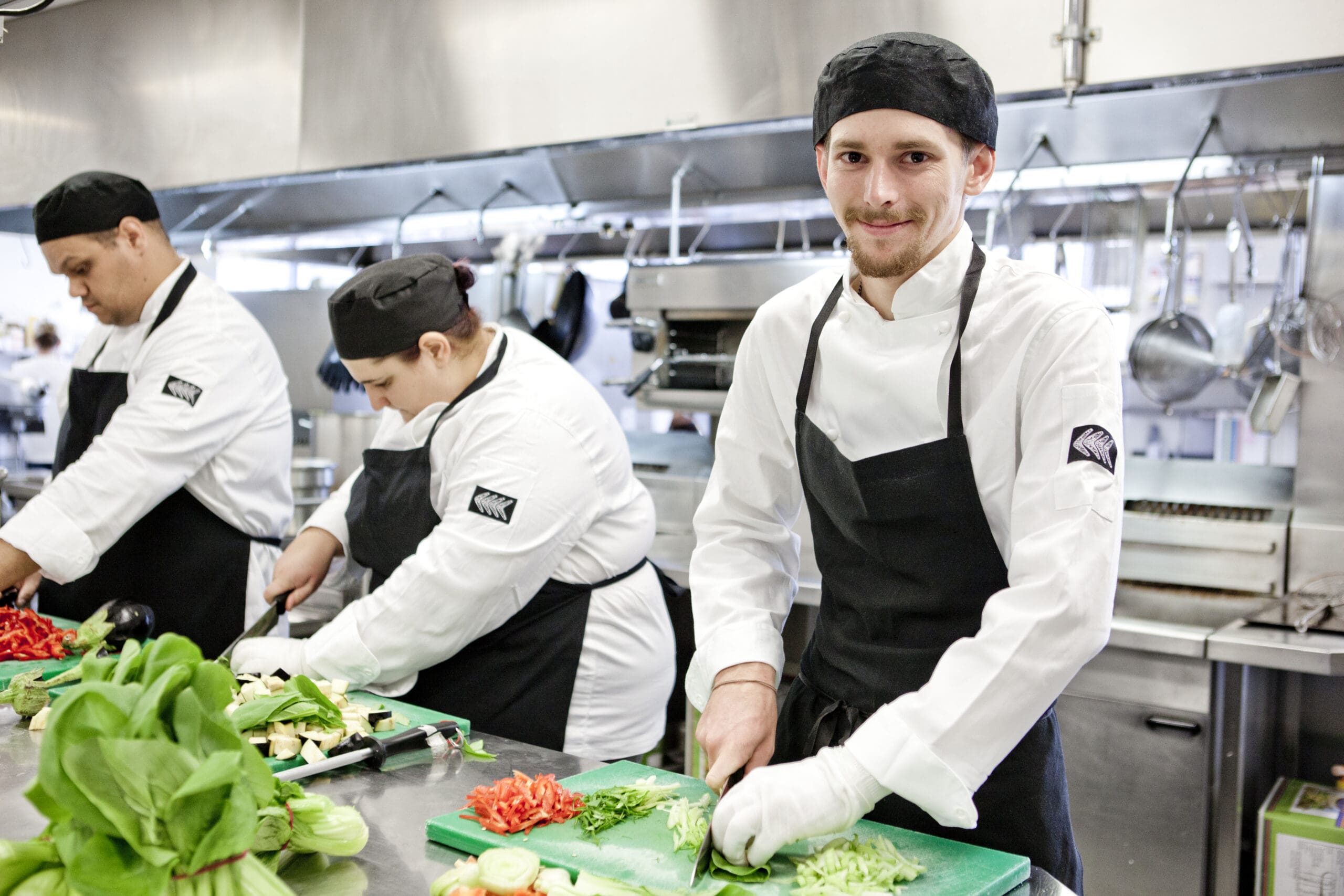 Three chefs working together in a professional kitchen, representing a diverse team